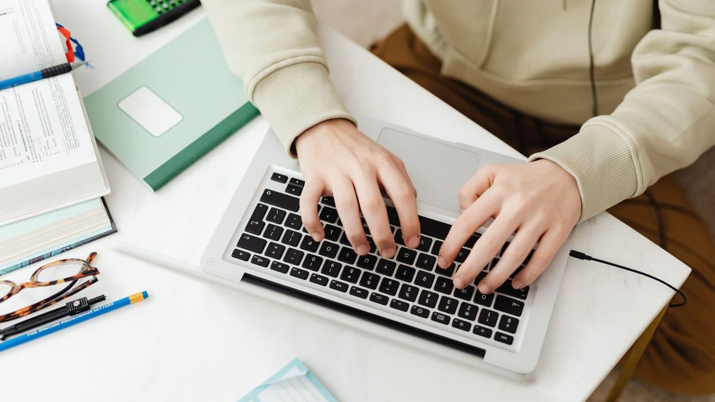 A student completing firearms coursework on a laptop at a kitchen table