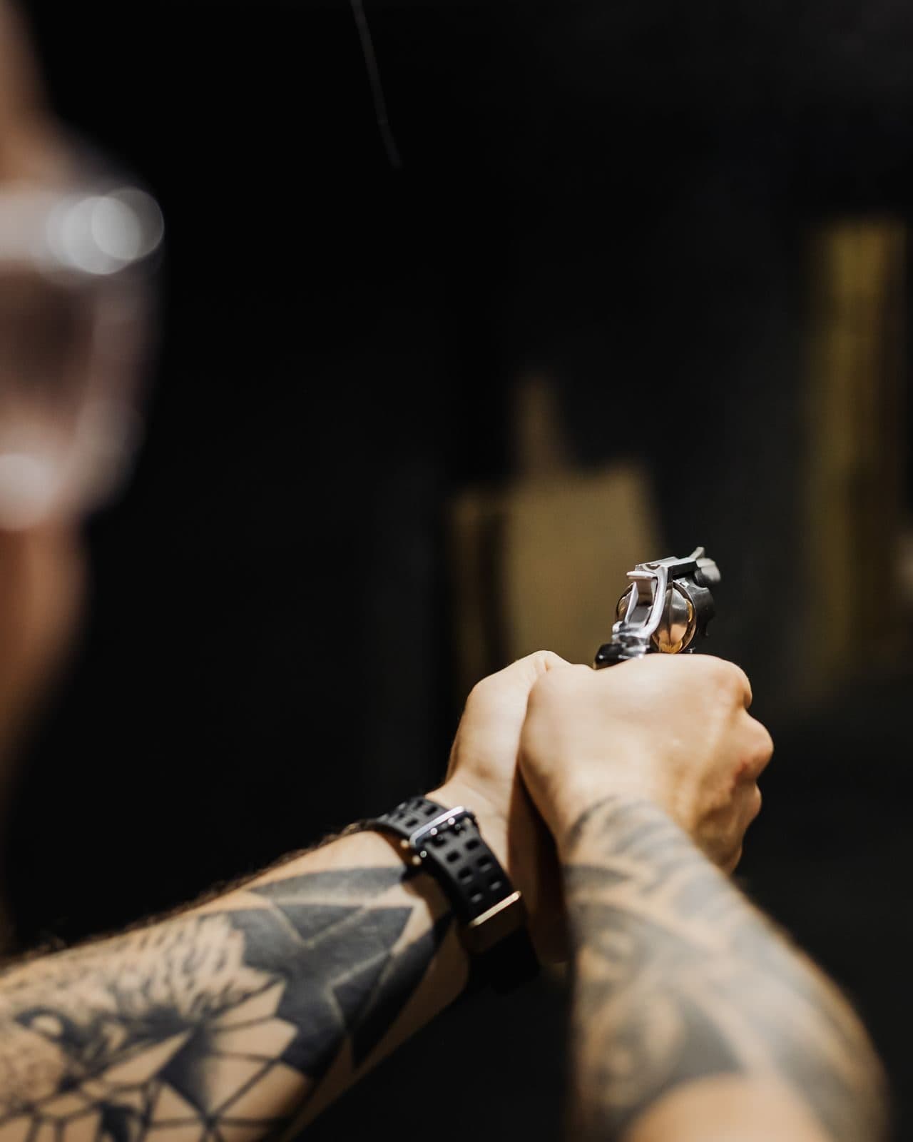 A firearms instructor coaching a student's grip and stance at an outdoor range